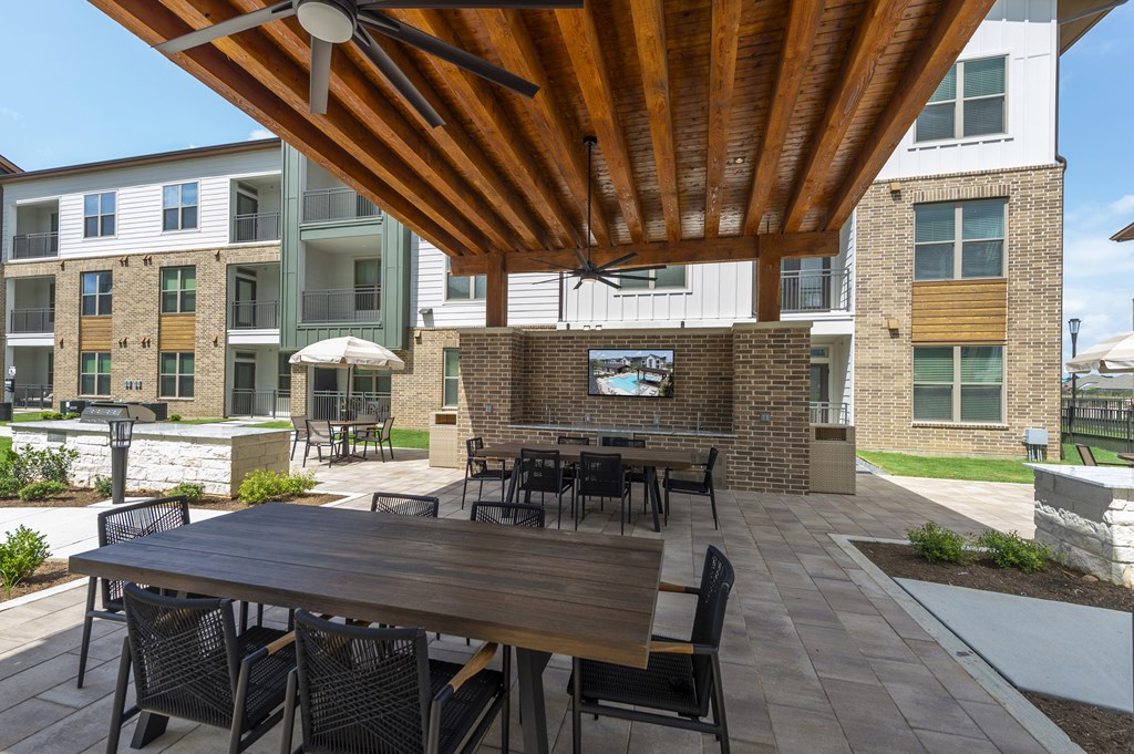 A wooden table with chairs under a wooden roof.