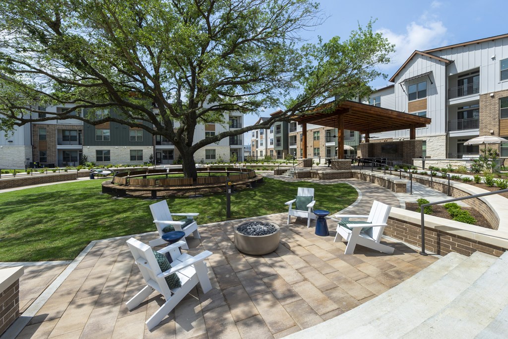 A patio with a fire pit and chairs.