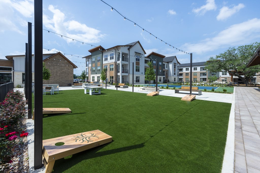A sunny day at a park with a bowling alley and apartment buildings in the background.