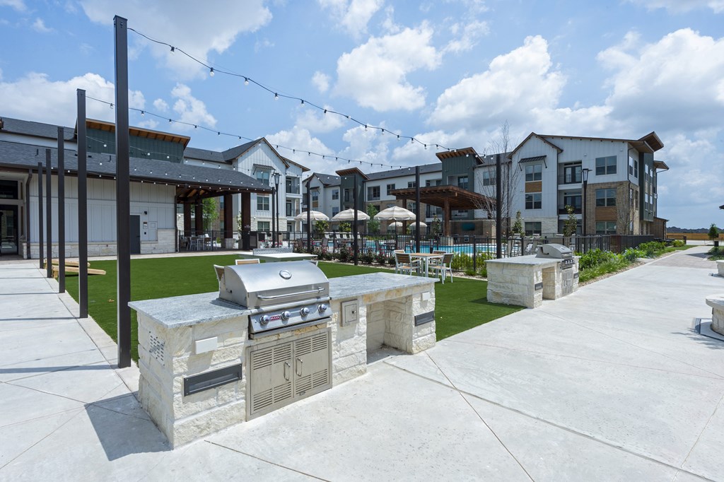 A patio area with a grill and a building in the background.