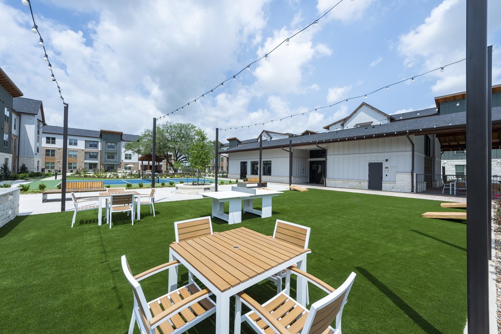A patio with a table and chairs is set up on a grassy area.