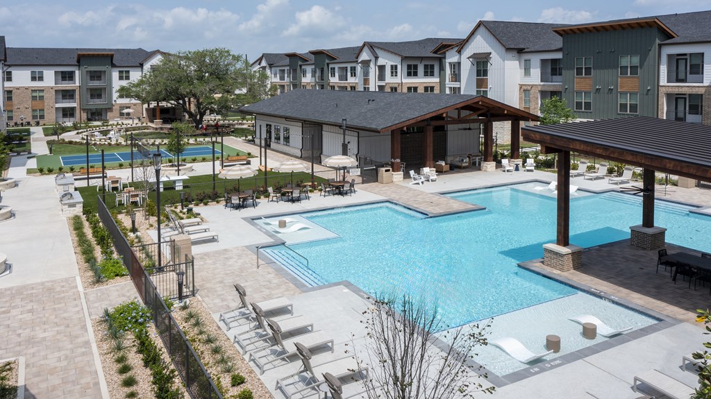 A large swimming pool surrounded by lounge chairs and umbrellas.