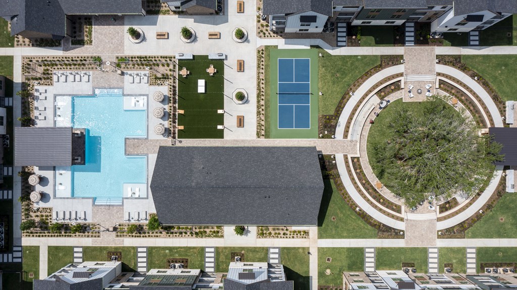 A bird's eye view of a residential area with a swimming pool and tennis court.