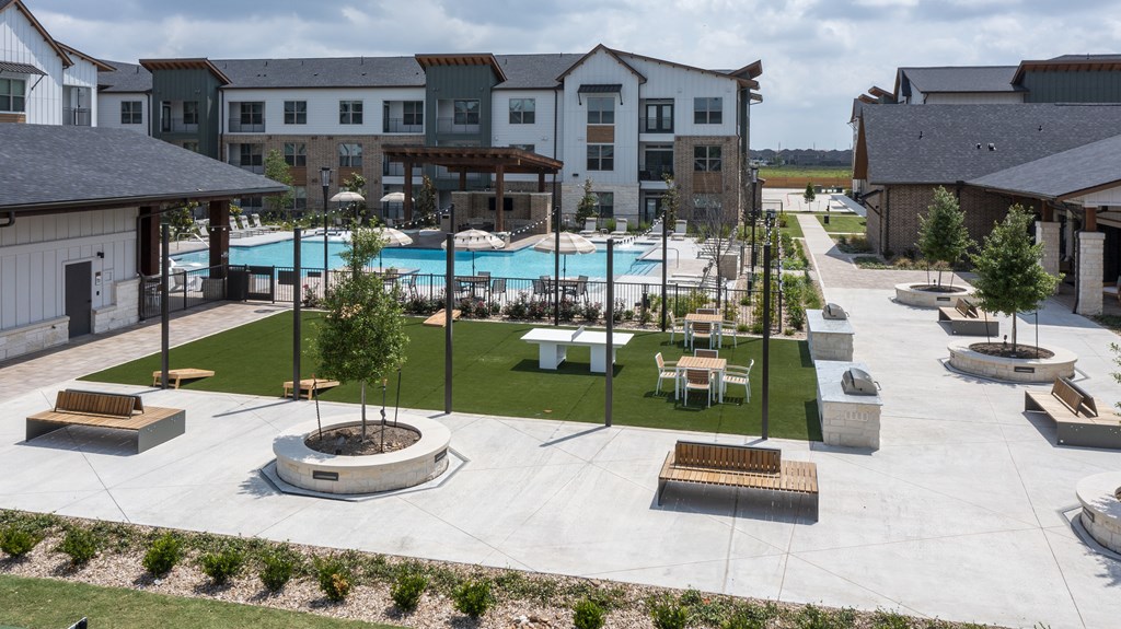 A large outdoor swimming pool surrounded by a grassy area and a building in the background.