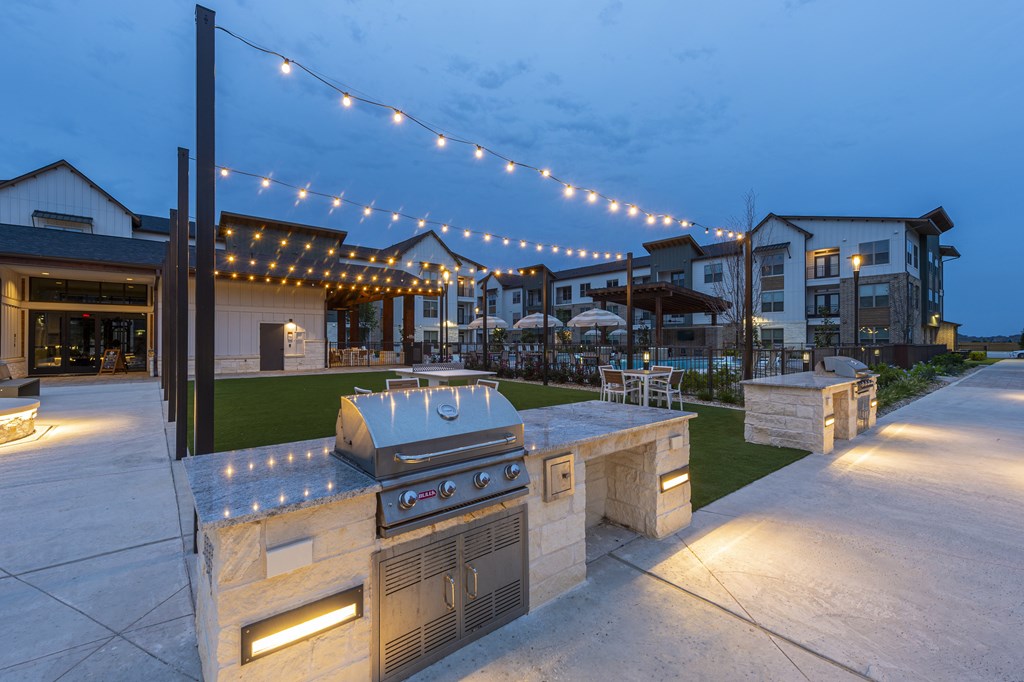 A BBQ grill is lit up at night in front of a building.