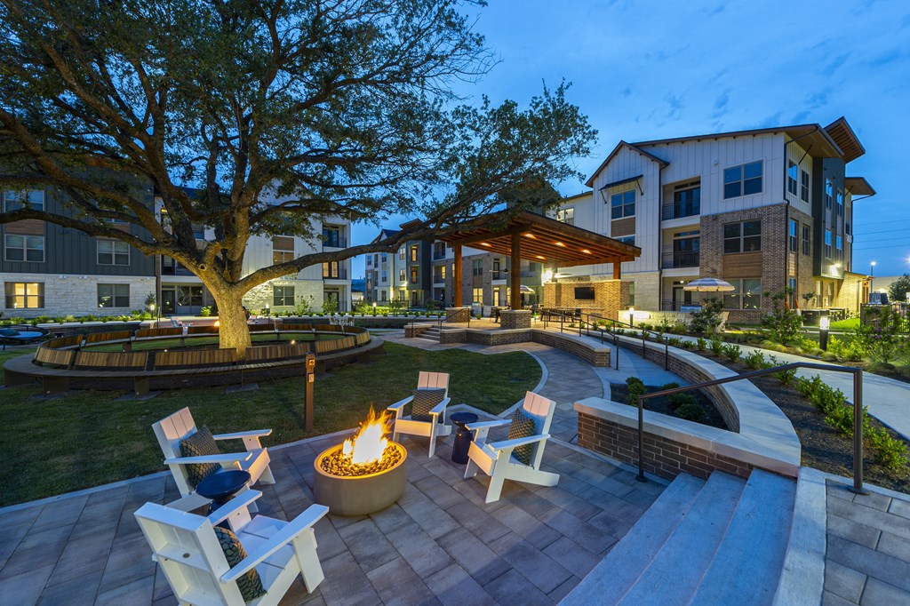 A fire pit sits in the middle of a patio surrounded by chairs.