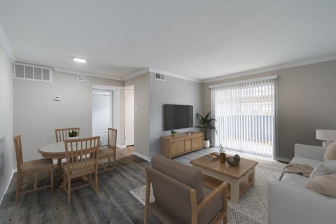 A living room with a white couch, a wooden dining table, and a television.