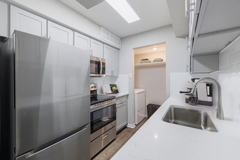 A modern kitchen with a stainless steel refrigerator and a sink.