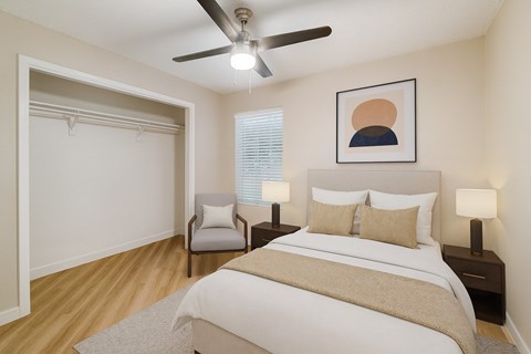 A bedroom with a bed, two lamps, a chair, and a painting on the wall.