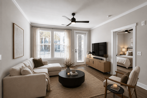 A living room with a beige couch, a coffee table, and a ceiling fan.
