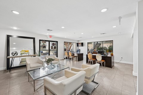 A spacious living room with a glass coffee table and white chairs.