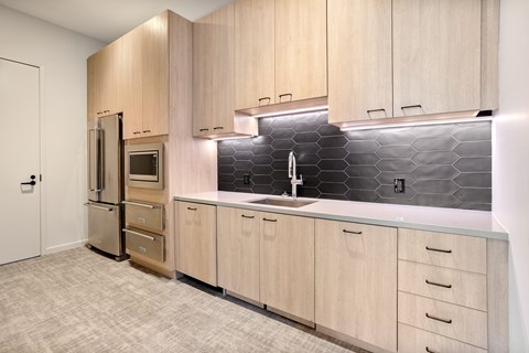 A kitchen with wooden cabinets and a black tile backsplash.