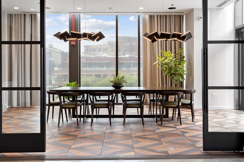 A dining room with a table and chairs in front of a large window.