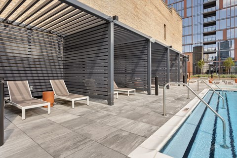 A pool area with sun loungers and a metal fence.