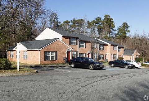 A black car is parked in front of a red brick building.