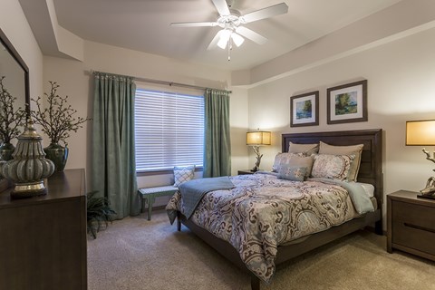 A bedroom with a large bed and a ceiling fan.