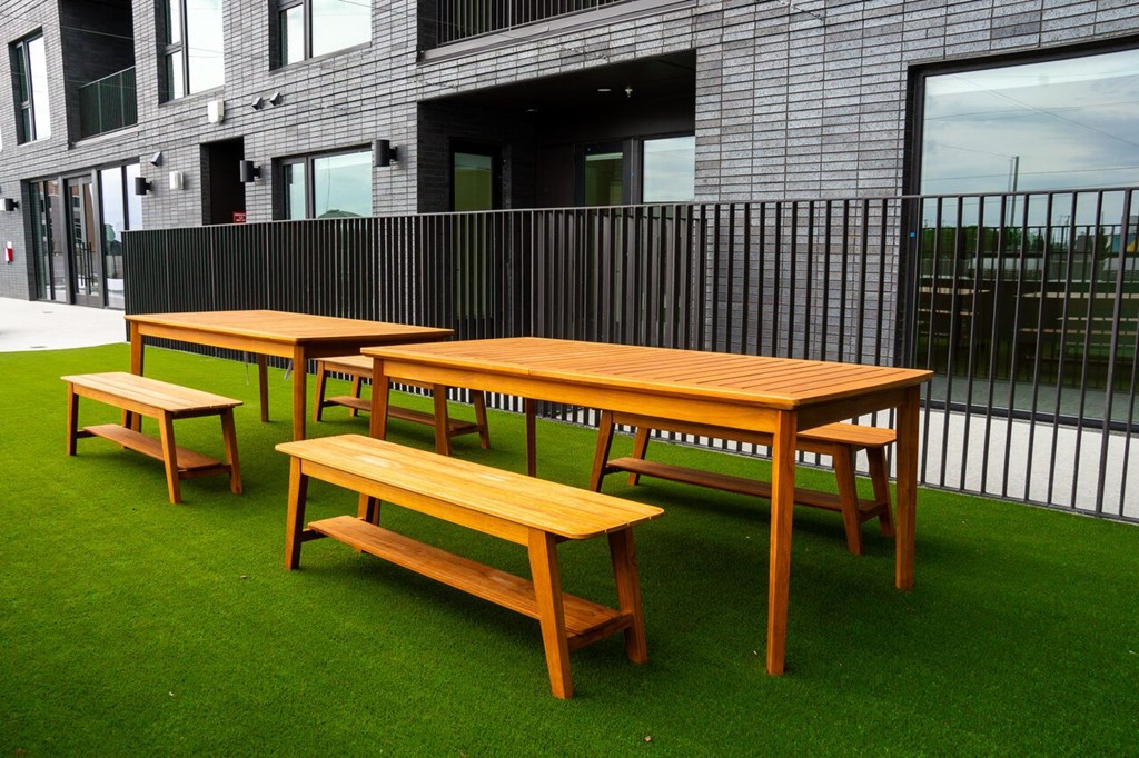 a row of wooden tables and benches on the grass