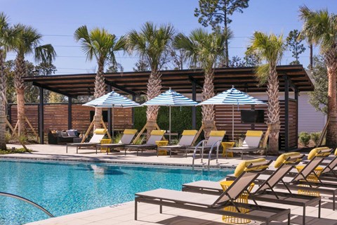 A pool area with sun loungers and umbrellas.