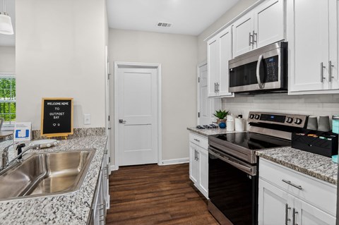 A kitchen with white cabinets and a black fridge.