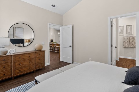 A bedroom with a large bed, a dresser, and a mirror.