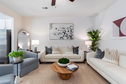 A living room with a white couch, a grey armchair, a wooden coffee table, and a painting on the wall.