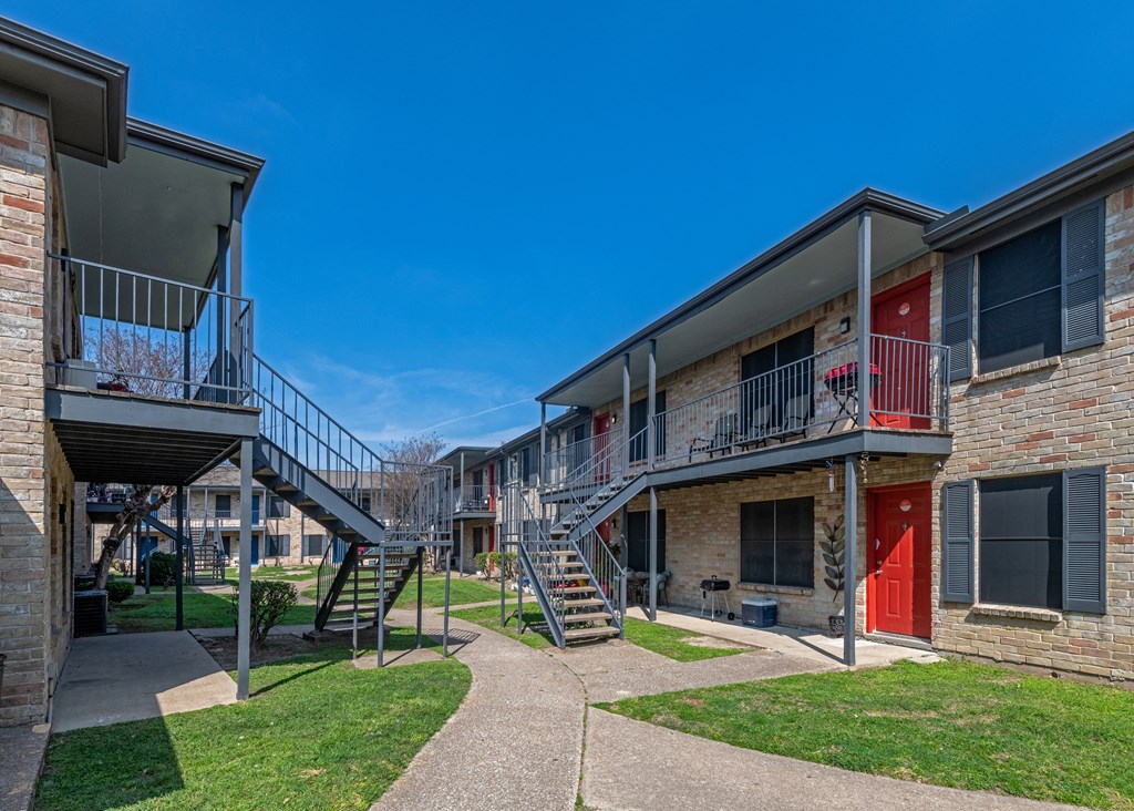 An exterior photo of a two-story apartment  building (Costa Mesa Apartments) with stairs