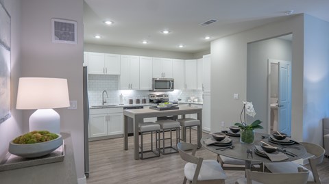 A modern kitchen with a dining table set for two.