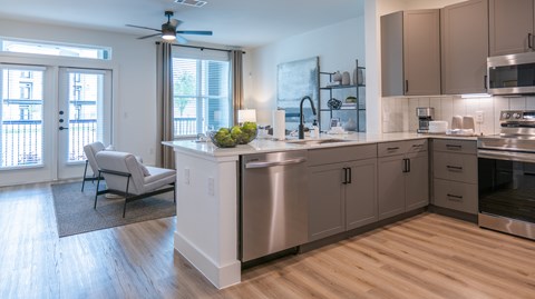 A modern kitchen with a large island and a balcony with a chair.