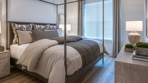 A bedroom with a large bed and a nightstand with a lamp.