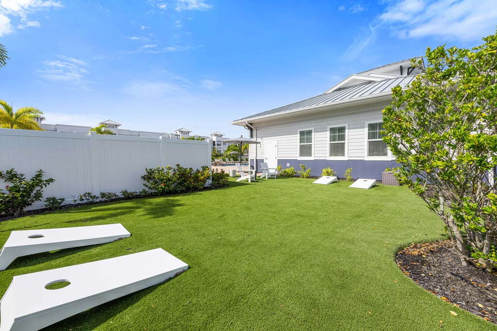 lawn area with corn hole game and a white fence