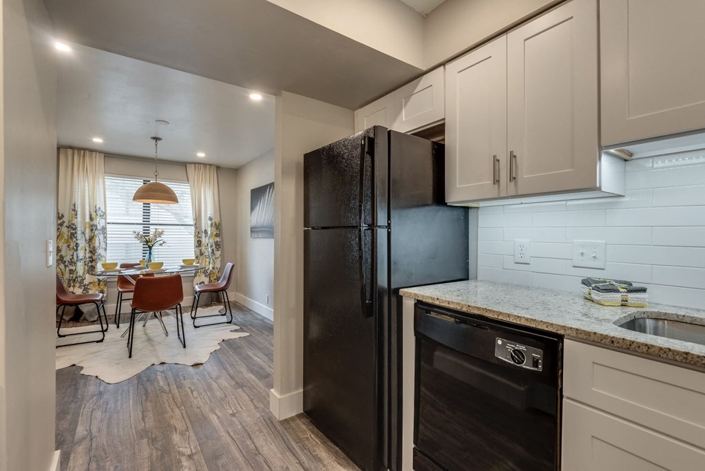 the kitchen and dining room of a home with a black refrigerator