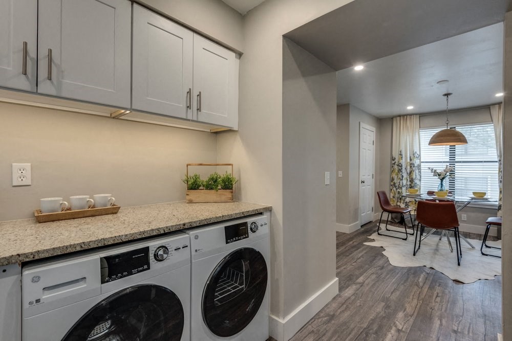a washer and dryer in a laundry room with a table and chairs