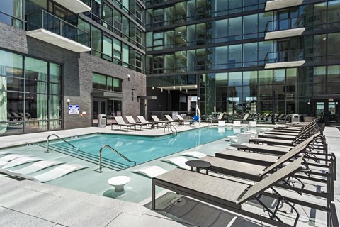 A large indoor swimming pool with lounge chairs and a modern building in the background.