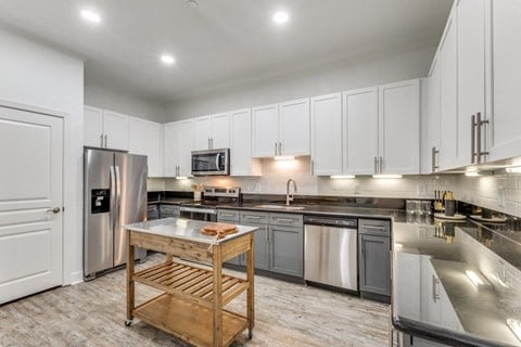 a large kitchen with stainless steel appliances and white cabinets