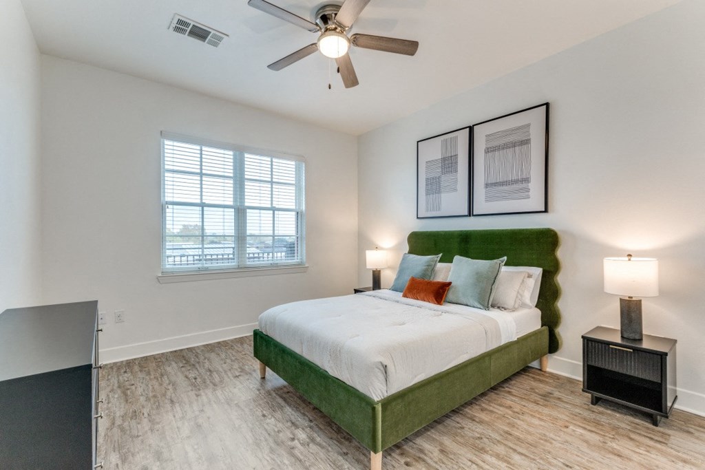 a bedroom with a green and white bed and a ceiling fan