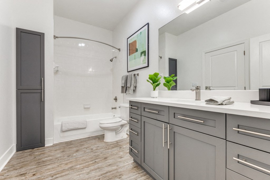 a bathroom with gray cabinets and a toilet and a shower