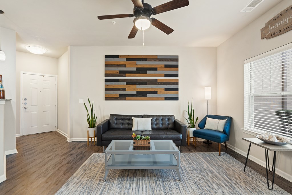 A living room with a black couch and a wooden wall hanging.