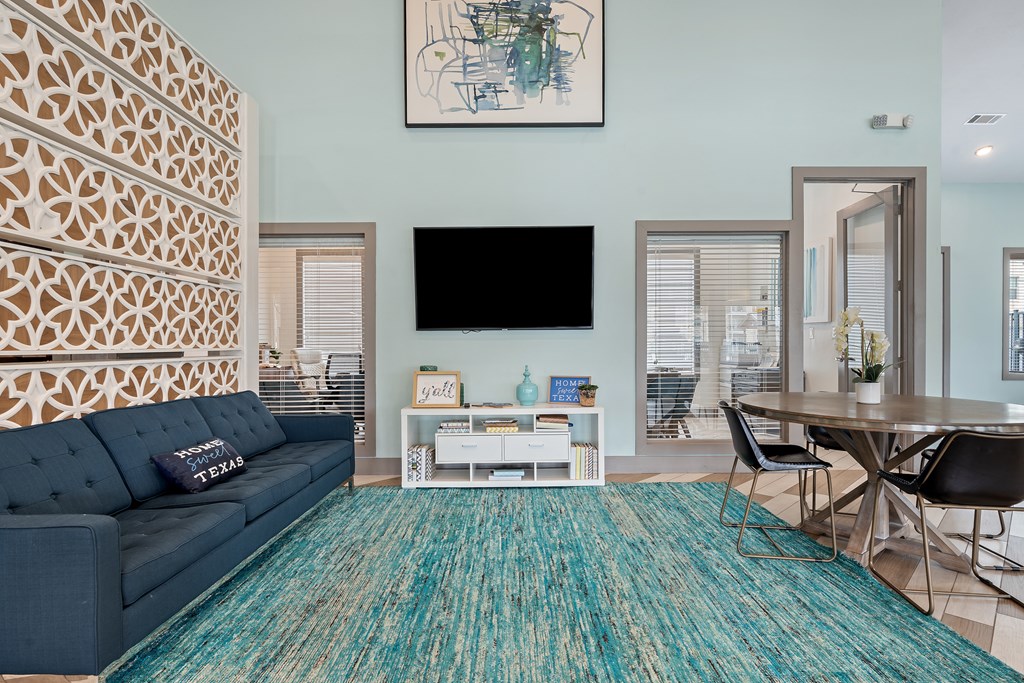 A living room with a blue couch and a patterned wall.
