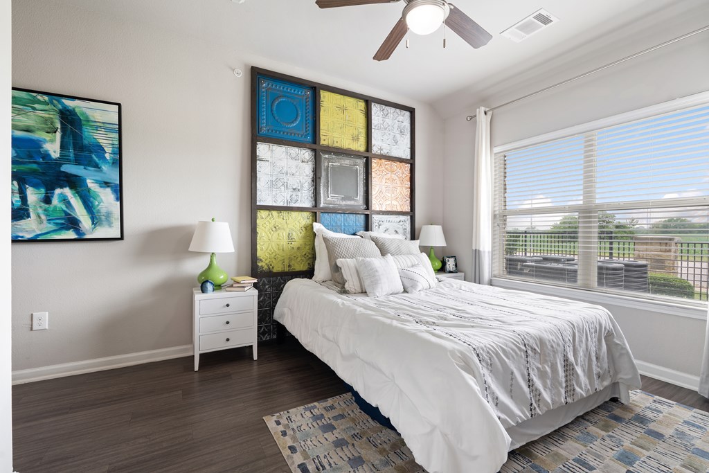 A bedroom with a bed, nightstand, and a painting on the wall.