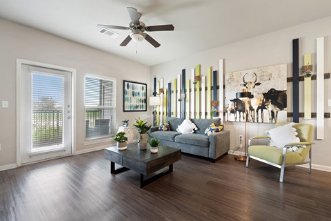 A living room with a grey couch, a coffee table, a yellow chair, and a painting on the wall.