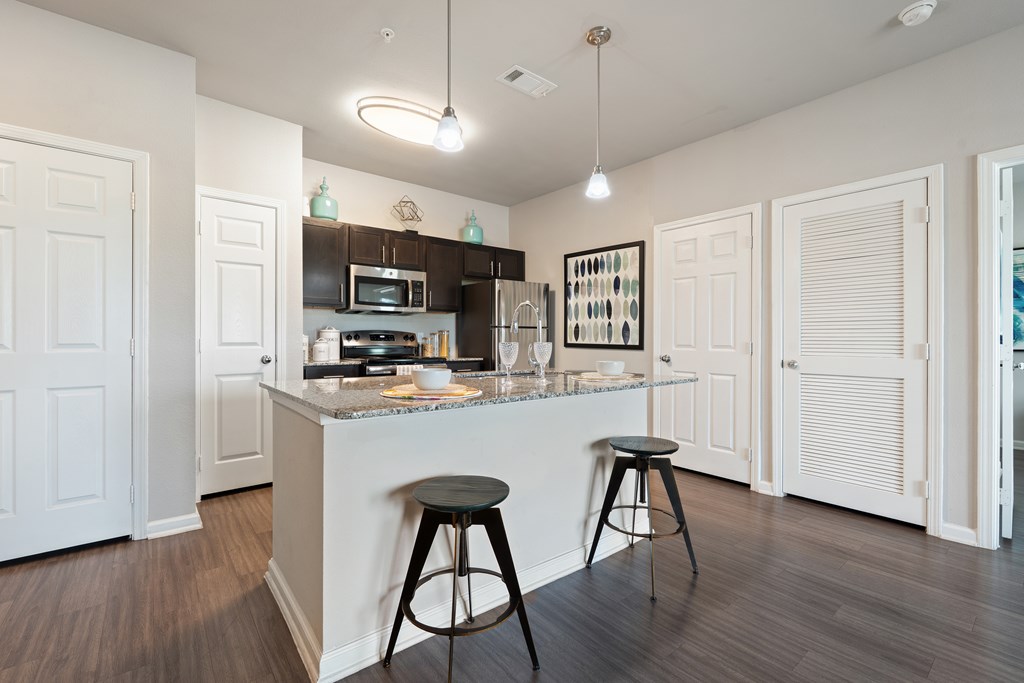 A kitchen with a bar stool in front of the counter.