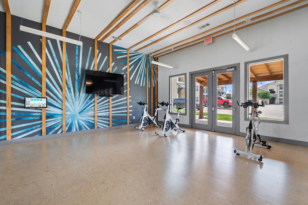 A room with exercise bikes and a TV on the wall.