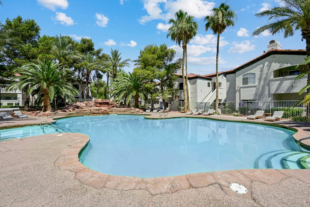 a large swimming pool with palm trees in the background