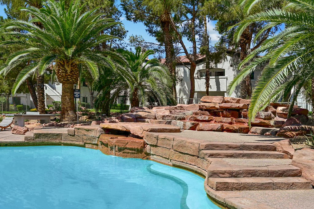 a resort style pool with a waterfall and rock steps