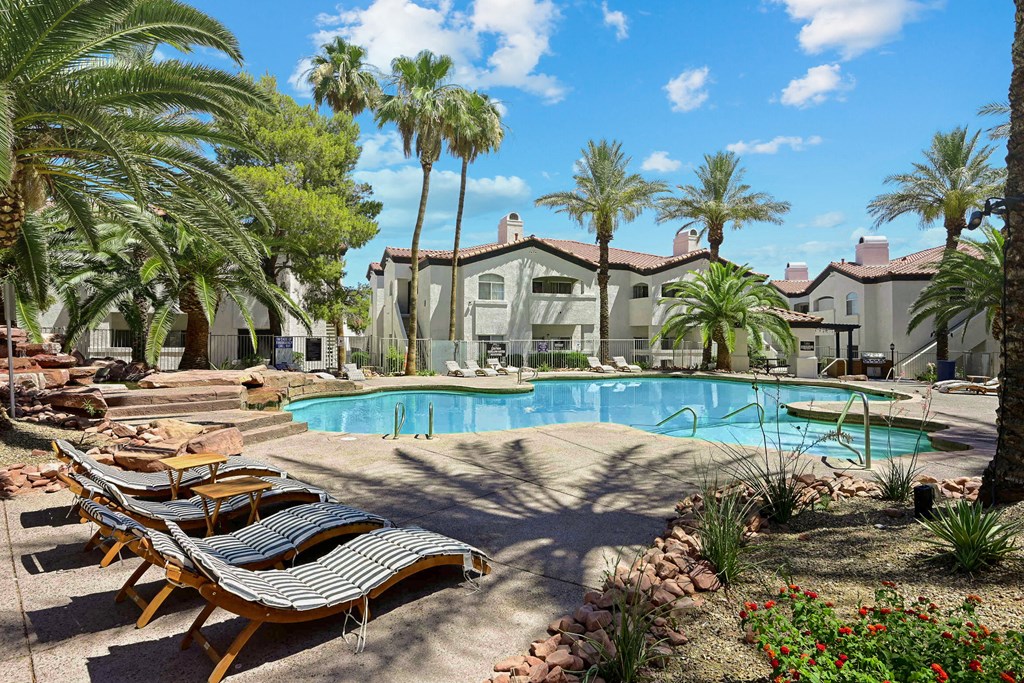 a swimming pool with lounge chairs and palm trees
