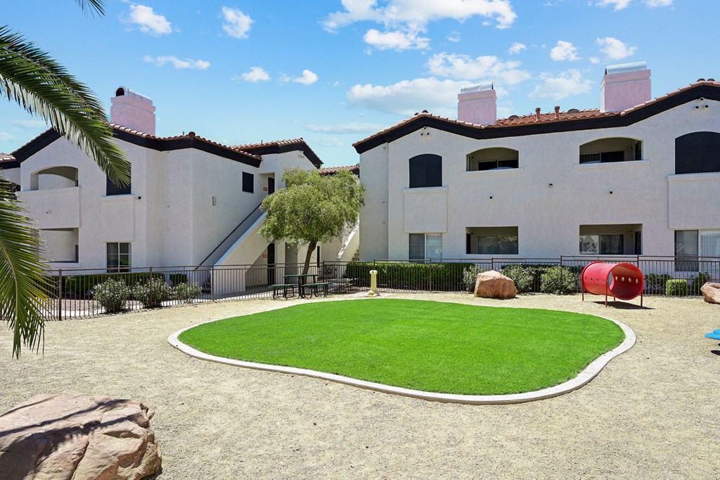 a yard in front of two white buildings with a grassy area in the middle