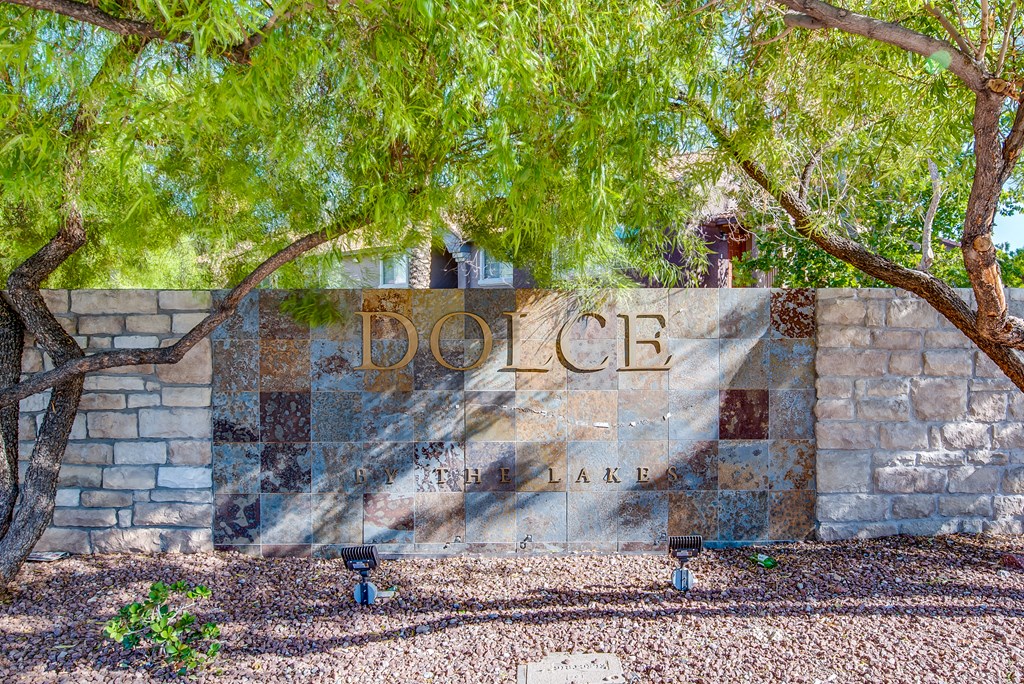 a sign for the dolce villa apartments on a stone wall with trees