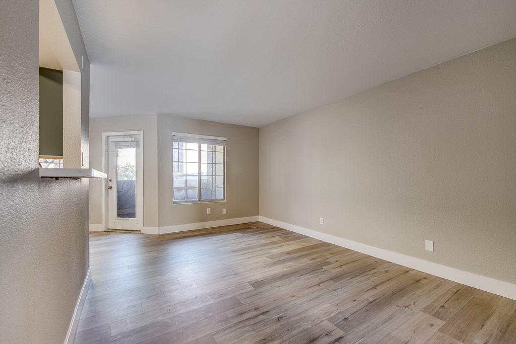 an empty living room with hardwood flooring and a window