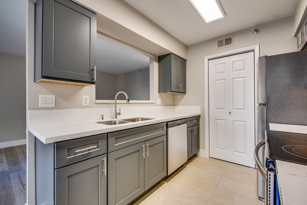 a kitchen with gray cabinets and a white counter top and a sink