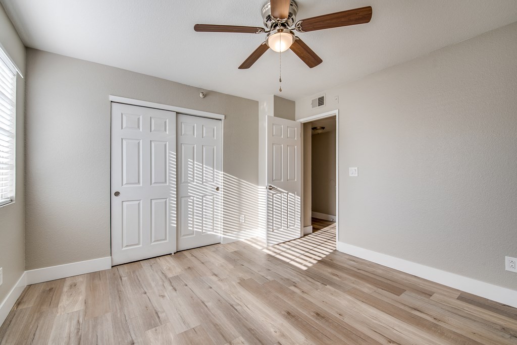 an empty living room with a ceiling fan and a staircase